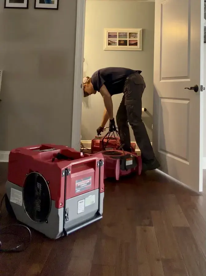Tech setting up an LGR dehumidifier and air movers in a Fontana hallway