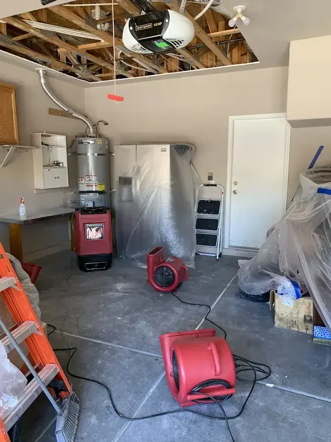 Air movers and a dehumidifier drying a garage with the ceiling opened after a water heater leak in Fontana
