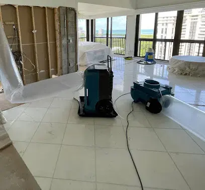 Dehumidifier and air mover drying a tiled room with the wall base opened in Fontana