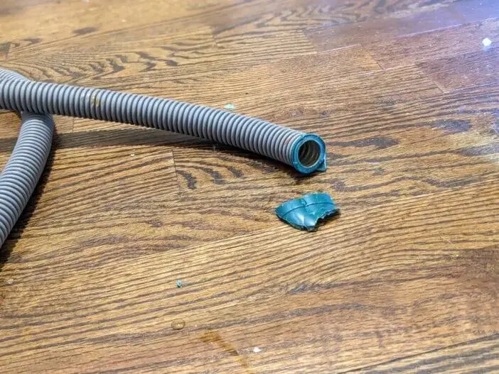 Split washing machine hose lying in a puddle on a Fontana hardwood floor