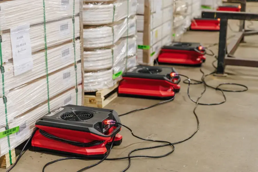 Air movers drying a warehouse aisle beside stacked pallets in Fontana
