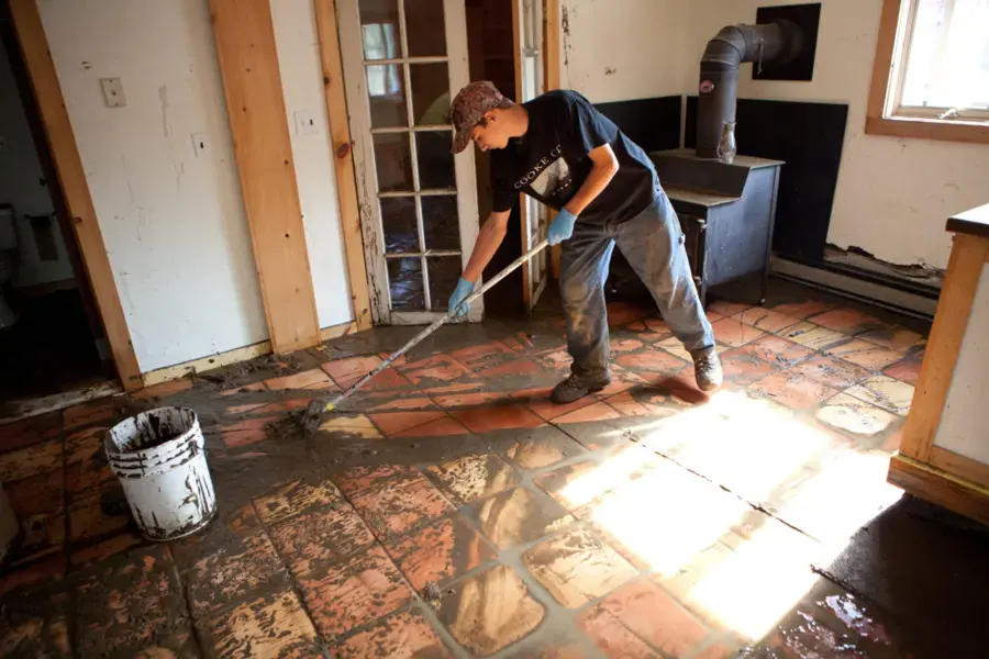 Mud and runoff being scraped off a tile floor after a flash flood near Fontana