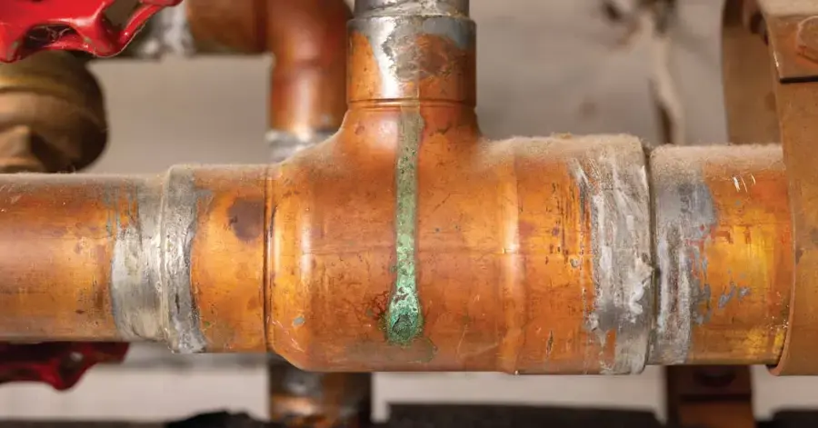 Green corrosion streak from a pinhole leak on a copper pipe fitting in Fontana